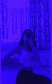 a girl is taking a selfie in front of a mirror with a purple light behind her .