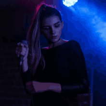 a woman singing into a microphone with a blue light behind her