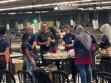 a group of people are gathered around a table with a man wearing a shirt that says dhl on it