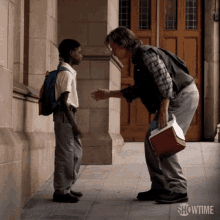 a man is shaking hands with a young boy in front of a building with showtime written on the bottom