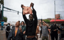 a man is holding a pig 's head above his head while a woman looks on .