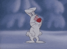 a cartoon rabbit with a red nose is standing on a snowy surface .