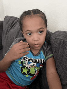 a young boy wearing a sonic shirt lays on a couch