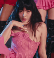 a woman in a pink dress with ruffles on the sleeves looks at the camera