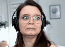 a woman with glasses and headphones is making a funny face .