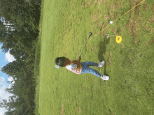 a little girl is swinging a golf club on a grassy field