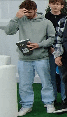 a man in a grey hoodie is holding a book with a sticker on it