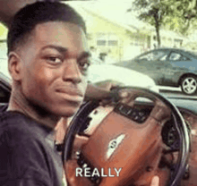 a man is sitting in the driver 's seat of a car and looking at the camera .