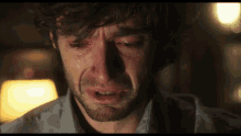 a man in a blue shirt is crying with tears running down his face