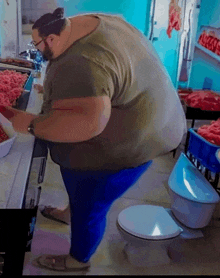 a very large man is standing on a toilet in a kitchen