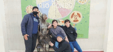 a group of young men pose in front of a statue of a woman with the word rio on it