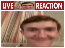 a man is smiling in front of a sign that says " live reaction "