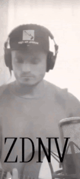 a man wearing headphones and a hat is standing in front of a microphone and the word zdnv is on the bottom