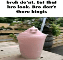 a strawberry milkshake with a cat on top of it on a table .