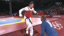 a man in a blue jacket with the word france on the back stands next to a woman in a taekwondo uniform