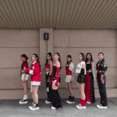 a group of women standing in front of a wall with one wearing a white shirt that says ' a ' on the front