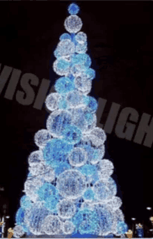 a christmas tree made of blue and white balls is lit up at night