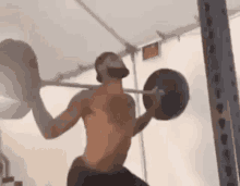 a man is lifting a barbell in a gym .