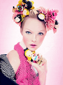 a woman in a pink top is holding a bottle of perfume