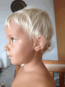 a little girl with short blonde hair has a pair of earrings in her ear