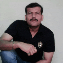 a man with a mustache wearing a black shirt has a badge on his chest