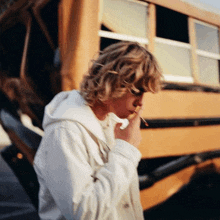 a person smoking a cigarette in front of a school bus