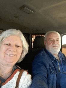 a man and a woman in a car smiling for the camera