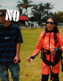 a man in a striped shirt stands next to a woman in an orange suit with the word sky on it