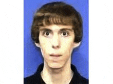 a young man with brown hair is wearing a black shirt and a blue background .