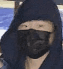 a close up of a person wearing a black mask and a hoodie .