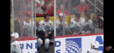 a group of hockey players are sitting on a bench with a banner that says uni