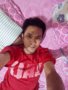 a man is laying on a bed with a red shirt that says uae