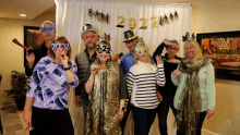 a group of people wearing new year 's eve masks and hats with the numbers 2022 on them