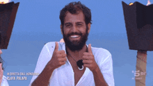 a man with a beard giving a thumbs up in front of a sign that says in diretta dall honduras playa palapa