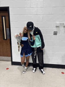 a cheerleader in a storm chasers outfit stands next to a man in a nike jacket