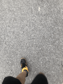a person wearing black and yellow nike shoes is walking on a road