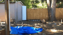 a blue tarp is laying on the ground in front of a fence