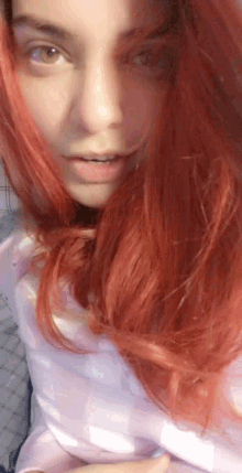 a woman with red hair and brown eyes looks at the camera