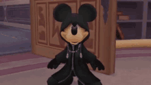 mickey mouse is wearing a black costume and standing in a room in a video game .