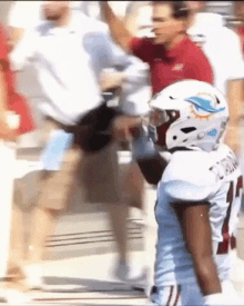 a football player wearing a helmet is standing in front of a crowd .