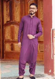 a man in a purple outfit is standing in front of a carved wooden door