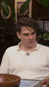 a man in a white shirt is sitting at a table with a bowl of food