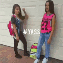 two young girls are standing next to each other in front of a garage door . one of the girls is wearing a chicago jersey .