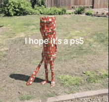 a person wrapped in red wrapping paper with the words i hope it 's a ps5 below them