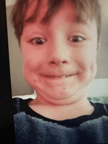 a young boy making a funny face with a blue shirt on