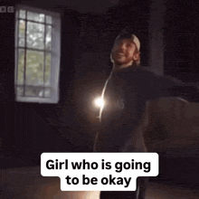 a man is standing in a dark room with his arms outstretched and a light behind him .