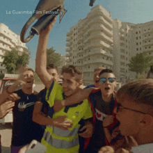 a group of young men are gathered around a man holding a trophy and the words la guarimba film festival are on the bottom