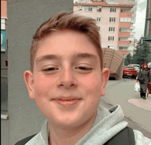 a young boy with a backpack smiles for the camera in front of a building