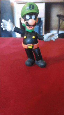 a mario figure with a green hat and black pants is standing on a red surface