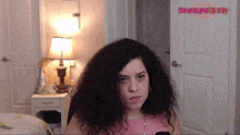 a woman with curly hair is standing in front of a door that has the word snapchat on it